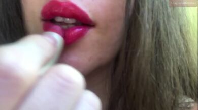 Innocent girl teasing with her fat lips, putting on red lipstick, sensually biting her lips, sucking