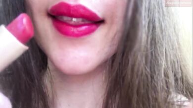 Innocent girl teasing with her fat lips, putting on red lipstick, sensually biting her lips, sucking